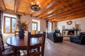 Ein Holzinnenraum mit einem Esstisch, Stühlen, einer Couch, einem Kamin und einem Fernseher.
