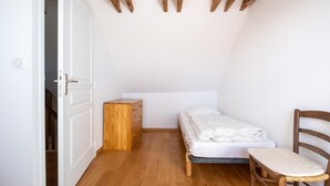 A small, single-bed room with a wooden dresser, a chair, and a door leading to another room. - Camillou's House (PRINSUEJOLS)
