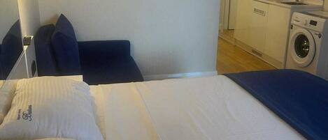 A hotel room with a bed, a small kitchenette, and a washing machine.