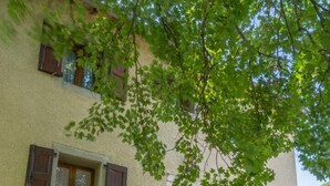 Un edificio de dos pisos con un balcón, una entrada pequeña y una ventana con contraventanas.