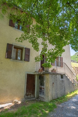 Ein zweistöckiges Gebäude mit Balkon, kleinem Eingang und einem Fenster mit Fensterläden.