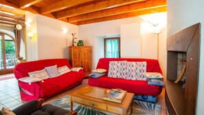 A living room with two red sofas, a wooden cabinet, a fireplace, and a tiled floor. - Domaine Rivière (6–7 people) (BRENOUX)
