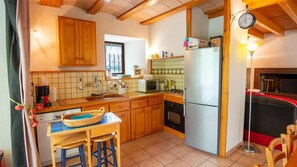 Eine kompakte Küche mit Holzausstattung, Spüle, Mikrowelle, Kühlschrank und einer Essecke mit Sitzhocker.