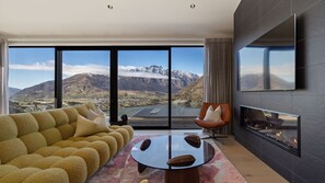 A modern living room with a sofa, a chair, a round table, and a fireplace. - The Middleton Escape (Queenstown)