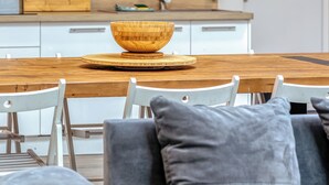 Une cuisine moderne dotée de deux micro-ondes encastrés, d’un pare-feu en bois et d’un coin repas avec une table en bois et des chaises blanches.