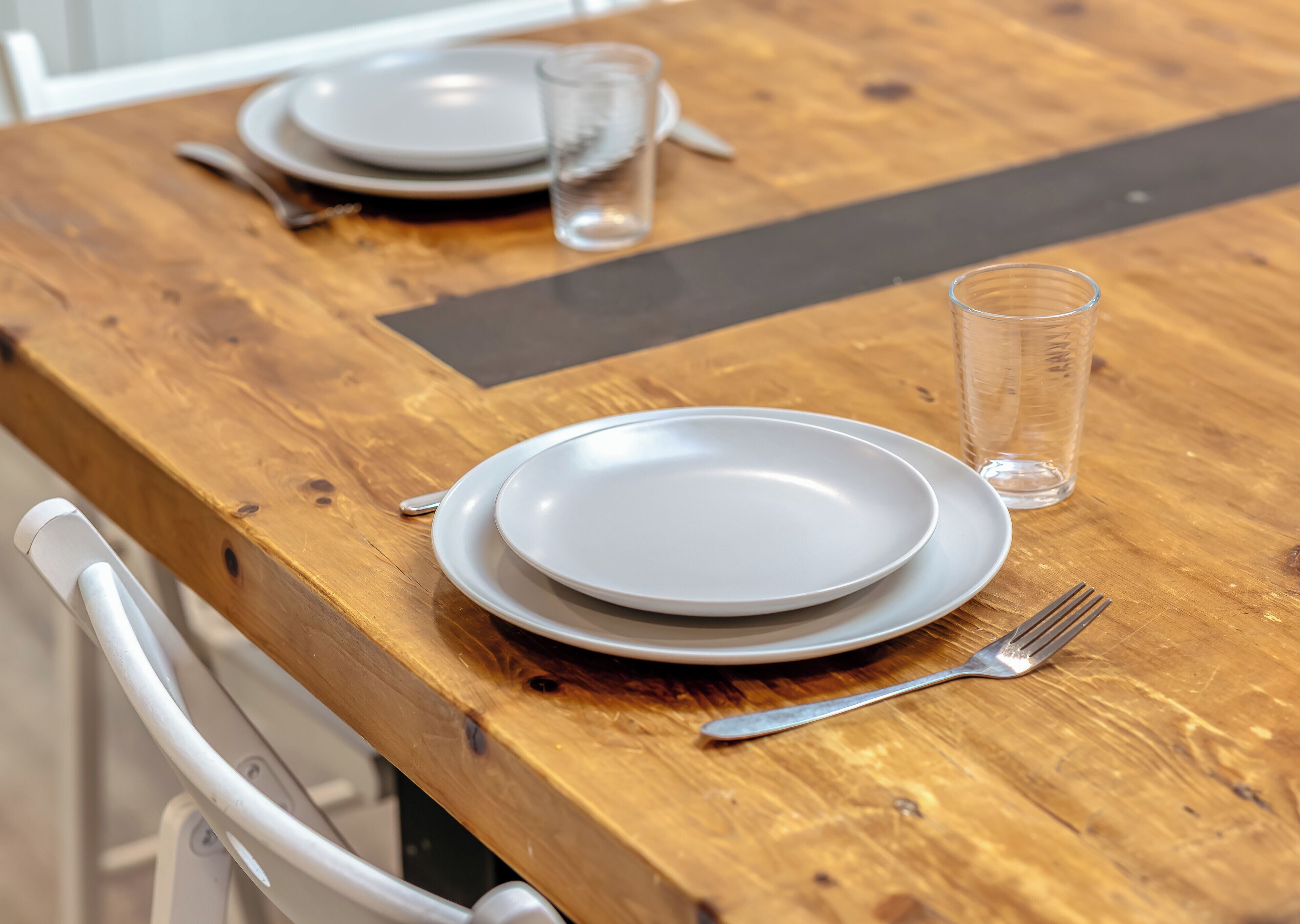 Uma mesa de madeira com dois pratos, um copo e talheres.