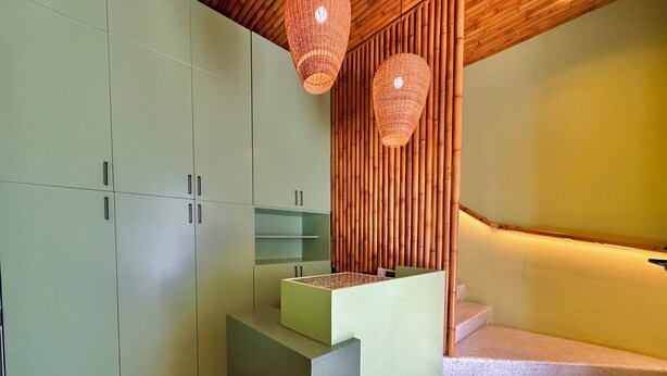 A modern kitchen with green cabinets, a wooden counter, and a bamboo wall. - Isabel Suites By YellowKey (Santo Domingo)