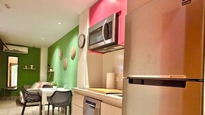 A modern kitchen with a refrigerator, microwave, and dining area with chairs and a table. - Isabel Suites By YellowKey (Santo Domingo)