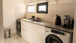 A compact kitchen with a stove, oven, sink, and a front-loading washing machine.