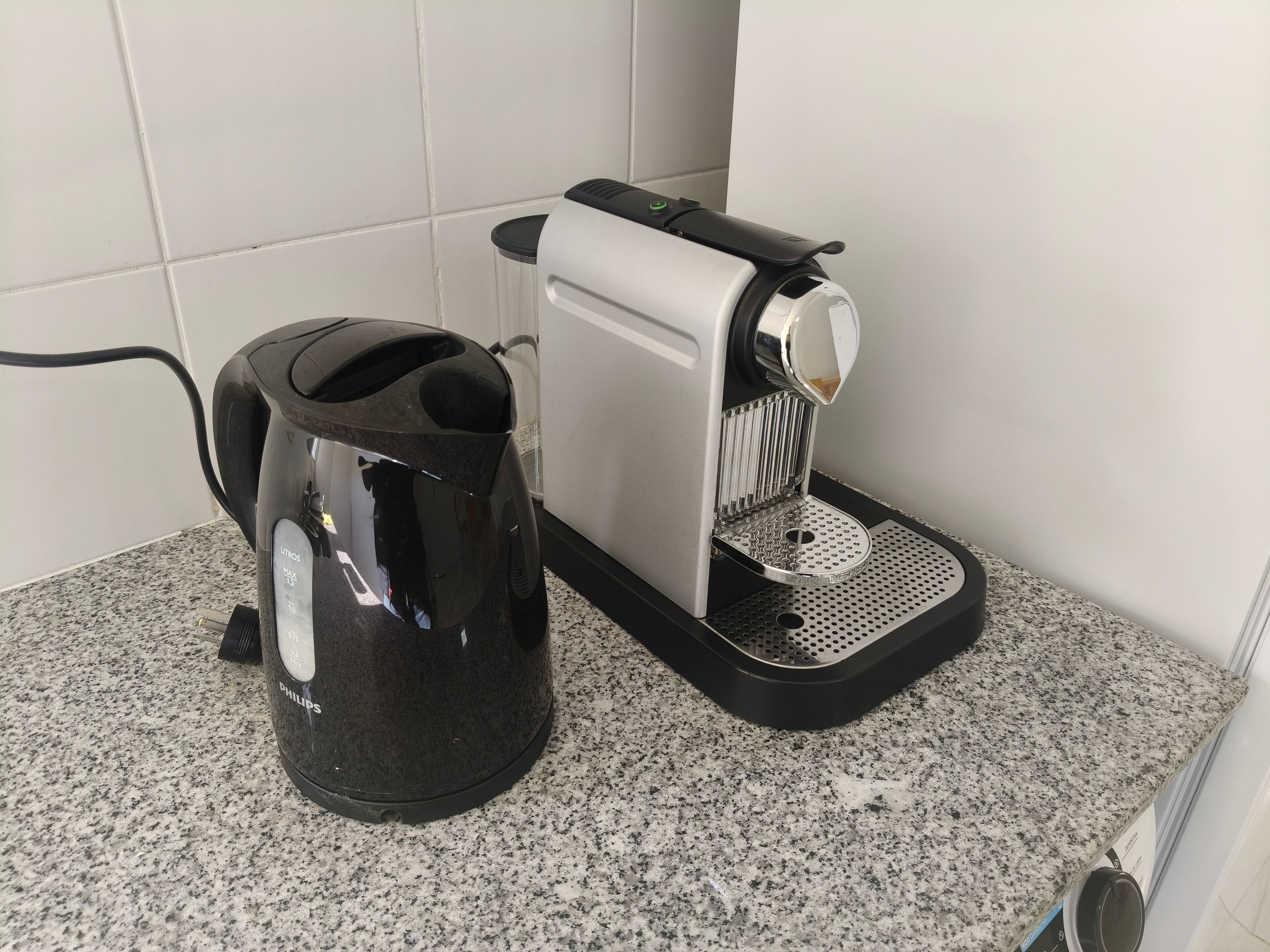 Una cafetera y un hervidor eléctrico negro sobre una encimera de granito.