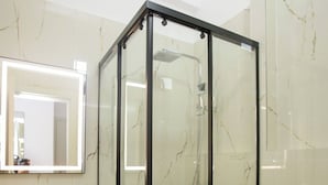 Une salle de bain avec une douche à parois de verre, un lavabo avec un miroir et des toilettes.