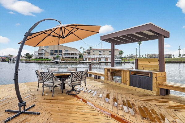 Eine Holzterrasse mit Tisch, Stühlen und einem großen Sonnenschirm sowie einer Holzkonstruktion.