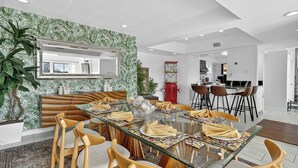 A modern dining area with a glass table, wooden chairs, and a patterned wall. - DaZzling Waterfront 3-bedroom Pool/Hot tub/Gym in N. Padre Island (Corpus Christi)