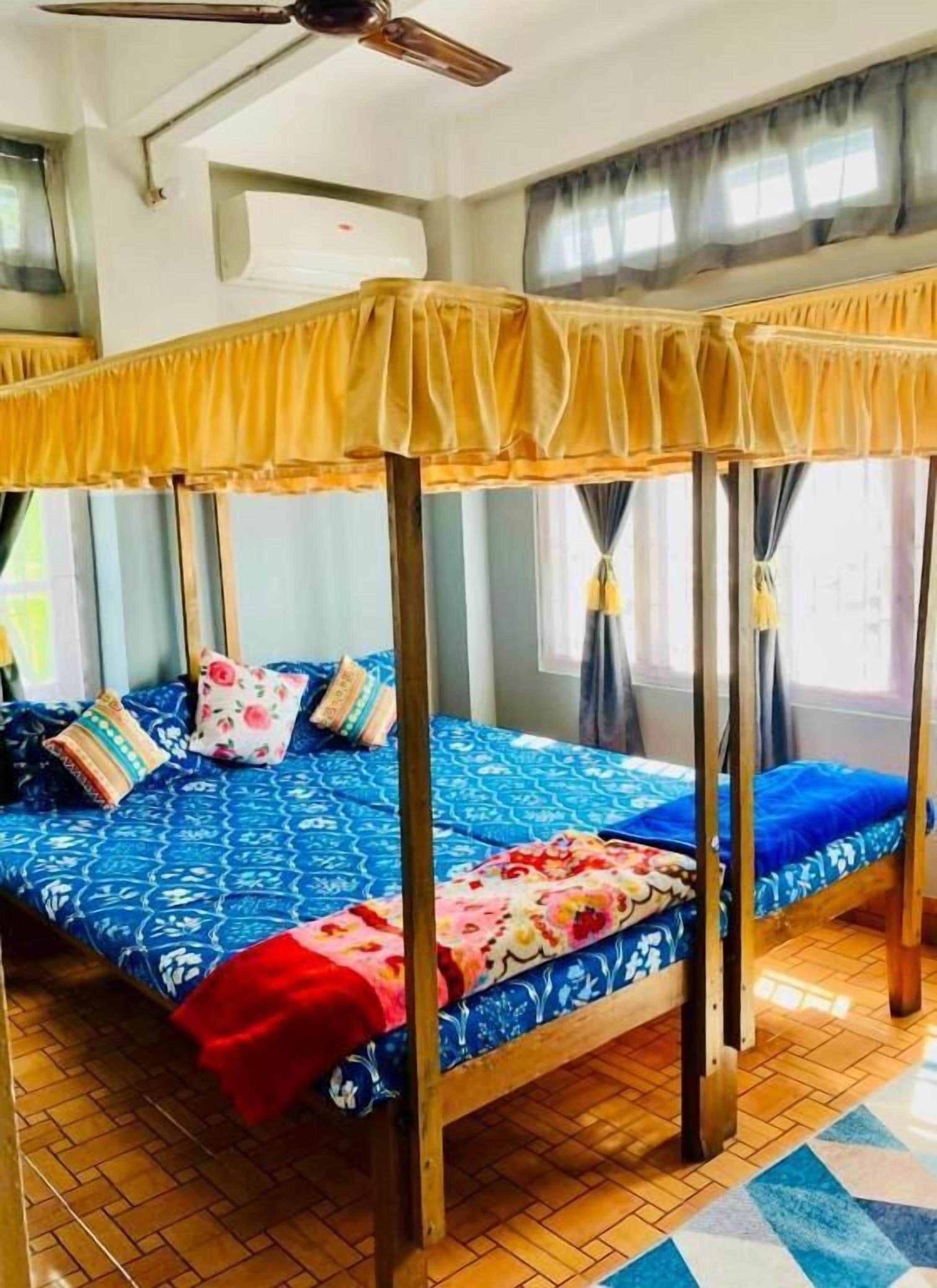 A room with a four-poster bed, a ceiling fan, an air conditioning unit, and a tiled floor.
