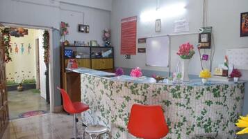 A reception area with a counter, red chairs, a whiteboard, and a bulletin board.