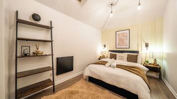 A bedroom with a bed, bedside tables, a shelf unit, a radiator, and a fluffy rug.