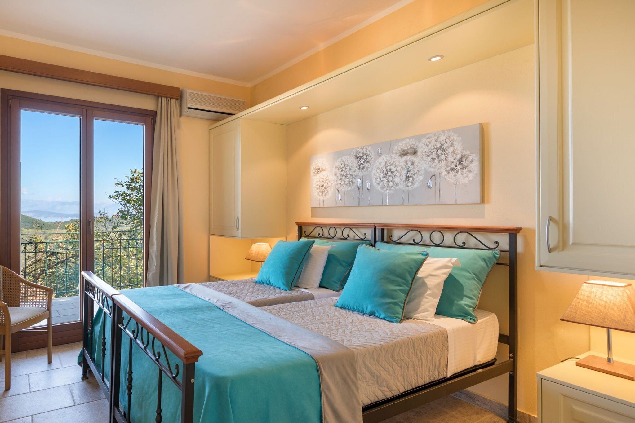 Una cama doble con vistas al exterior, una silla, una mesita de noche con una lámpara y una obra de arte en la pared.