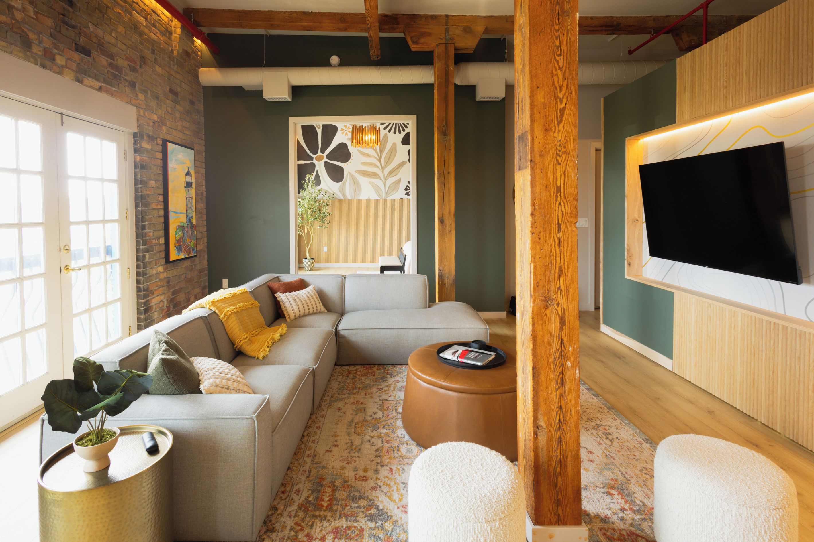 A modern living room with a sectional sofa, a coffee table, a TV, and a patterned rug.