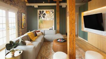 A modern living room with a sectional sofa, a coffee table, a TV, and a patterned rug.