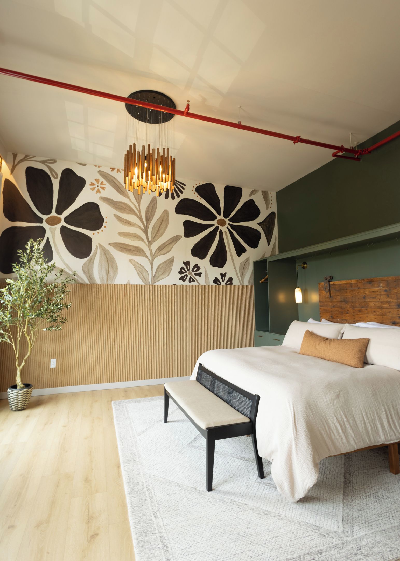 A modern bedroom with a large bed, a bench, a potted plant, and a unique wall design.