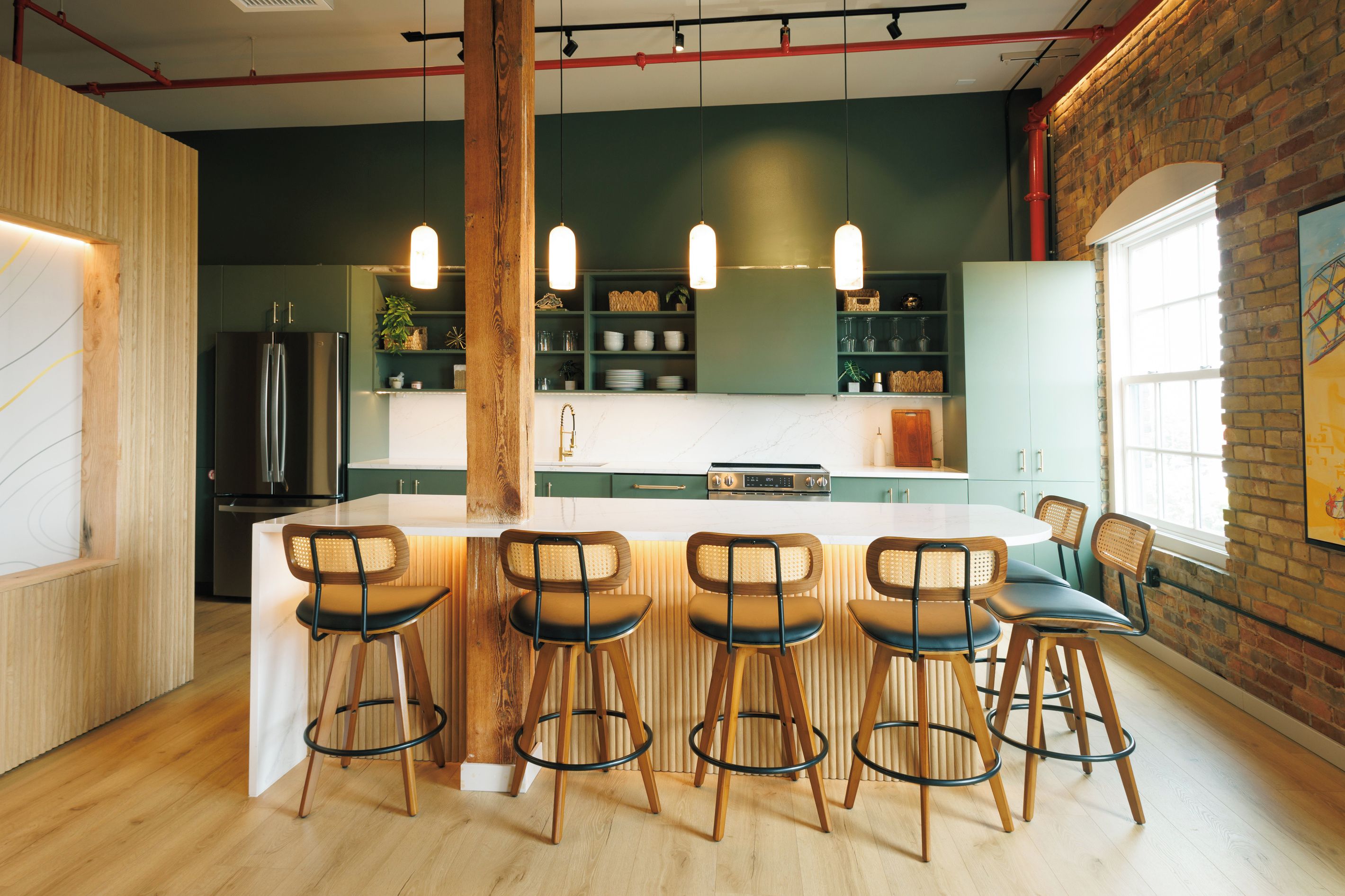 Une cuisine moderne dotée d’un îlot central, de tabourets de bar et de luminaires suspendus.