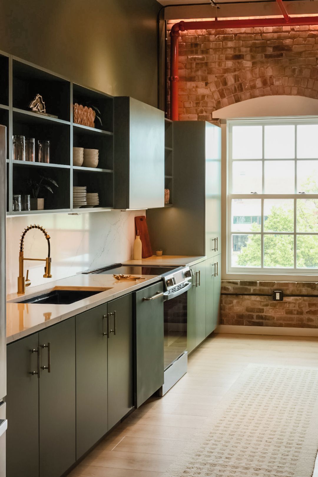 A modern kitchen with a marble countertop, stainless steel appliances, and a brick wall.