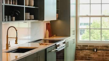 A modern kitchen with a marble countertop, stainless steel appliances, and a brick wall.