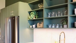 Una cucina moderna con frigorifero in acciaio inossidabile, un piano di lavoro bianco e mobili verde acqua.