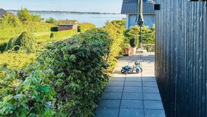 Un jardí amb un camí pavimentat, un edifici petit i vistes a una massa d'aigua.