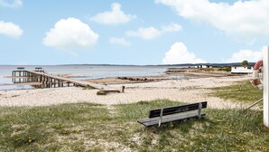 Una platja amb un pont de fusta, una banca i un bou salvavides.