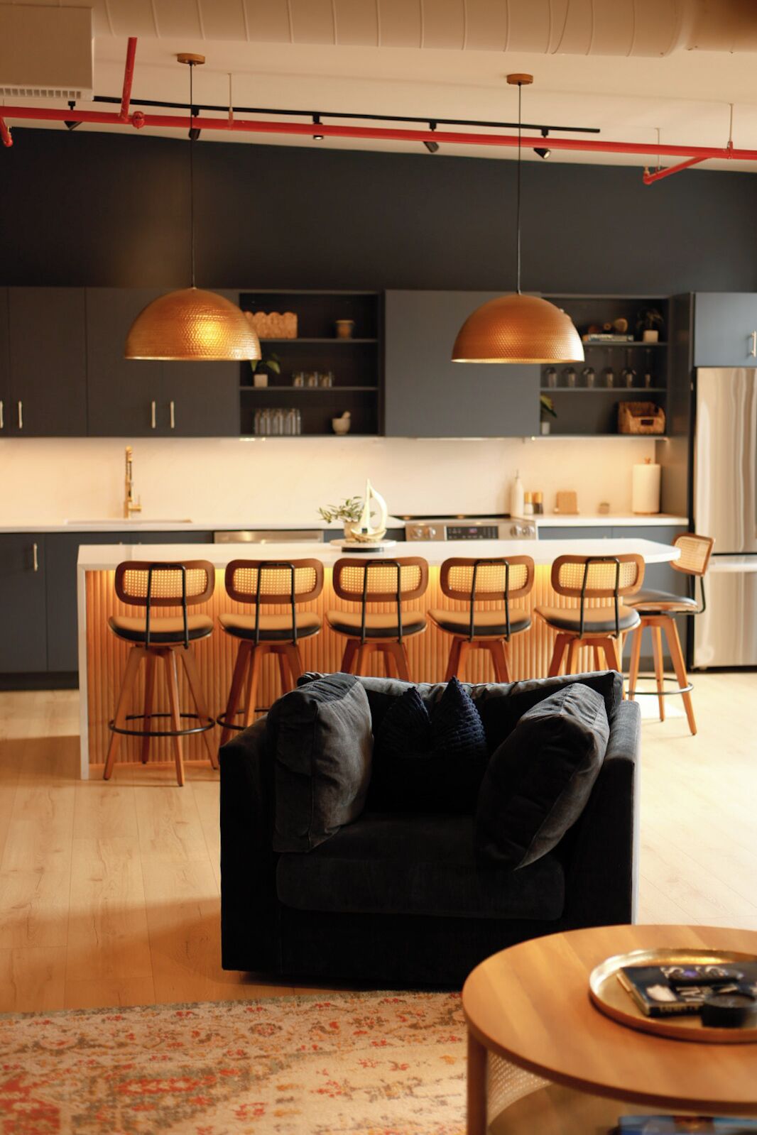 A modern kitchen with a central island, bar stools, and pendant lighting.
