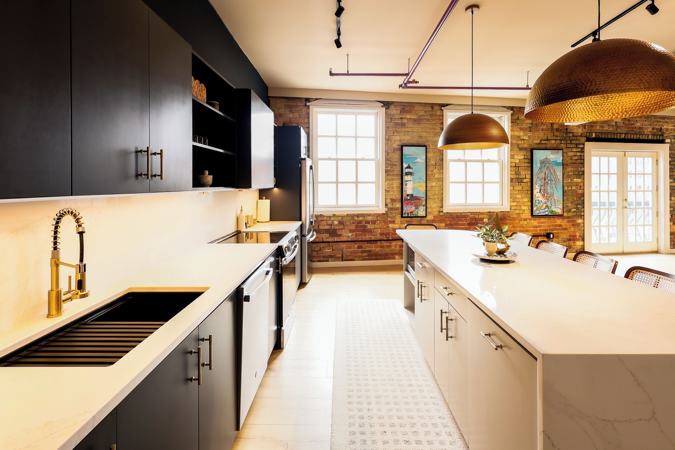 A modern kitchen with a central island, dark cabinetry, and a brick wall.