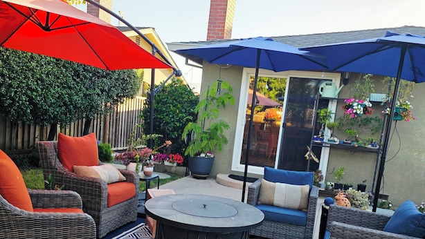 A patio with wicker furniture, a round table, and potted plants.