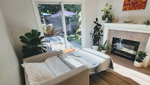 A bedroom with a bed, a fireplace, and a view of the outdoors.