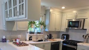 A modern kitchen with white cabinets, a stainless steel stove, and a large island with bar stools.