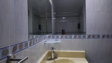 Un baño con un lavabo color beige, un espejo y una pared de azulejos con un borde decorativo.