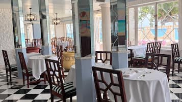 A dining area with checkered flooring, white tablecloths, and wooden chairs.