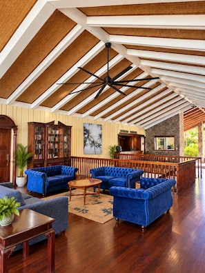 A spacious lobby with a high ceiling, wooden beams, and a central seating area with blue sofas.