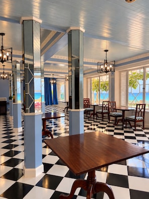 A hotel lobby with checkered flooring, mirrored pillars, and a view of the ocean. - Sunny Beach Inn (Ocho Rios)