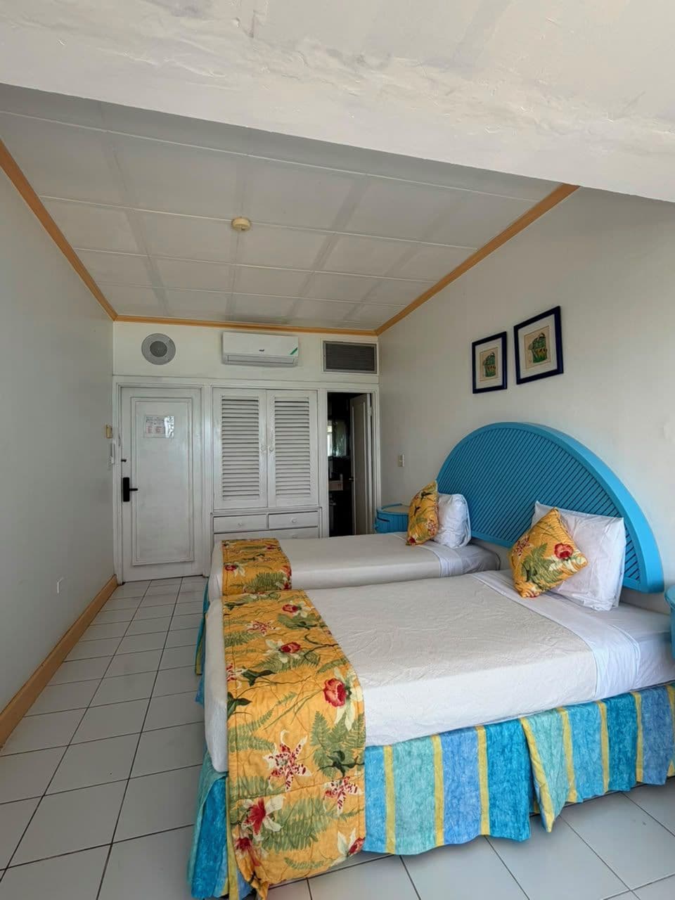 Een hotelkamer met twee bedden, een kledingkast en een deur.