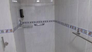 A small, tiled bathroom with a shower, toilet, and a towel rack.