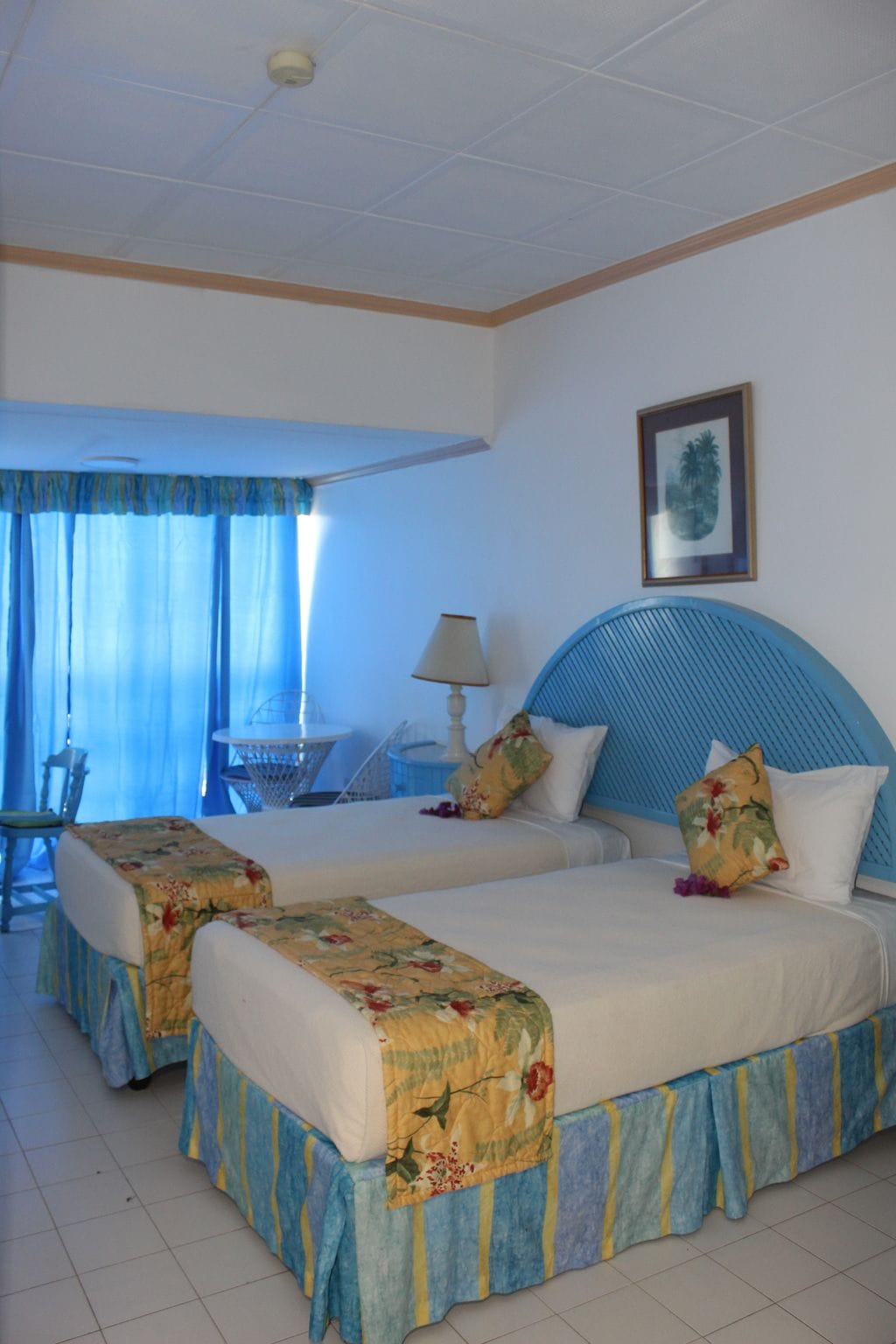 A hotel room with two beds, a dining area, and a view of the sea.