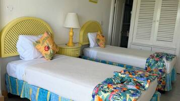 Una habitación con dos camas, cada una con cubrecama floral, cabecero amarillo y lámpara de noche.