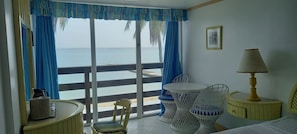 A room with a balcony, a bed, a chair, a table, and a lamp. - Sunny Beach Inn (Ocho Rios)