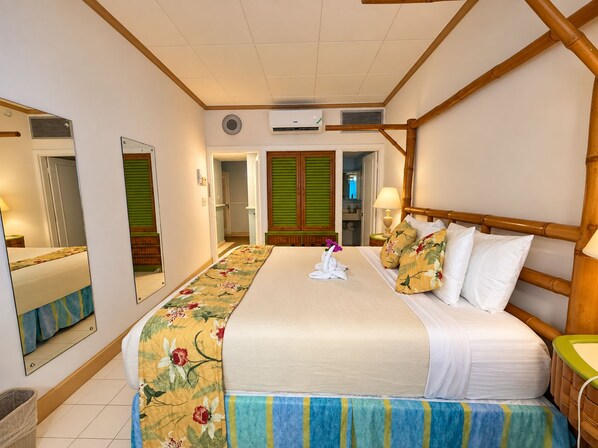 A hotel room with a bed, a mirror, a bathroom, and a green door.