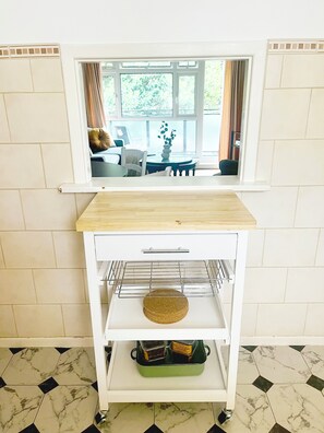 Eine Küchenzeile mit Holztischplatte, einem weißen Schrank mit Drahtgestell und einem gefliesten Boden.