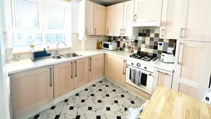 A kitchen with a gas stove, oven, microwave, and a sink. - Bright and Cozy London Apartment (London)