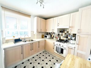 Eine Küche mit Gasherd, Backofen, Mikrowelle und Spüle.