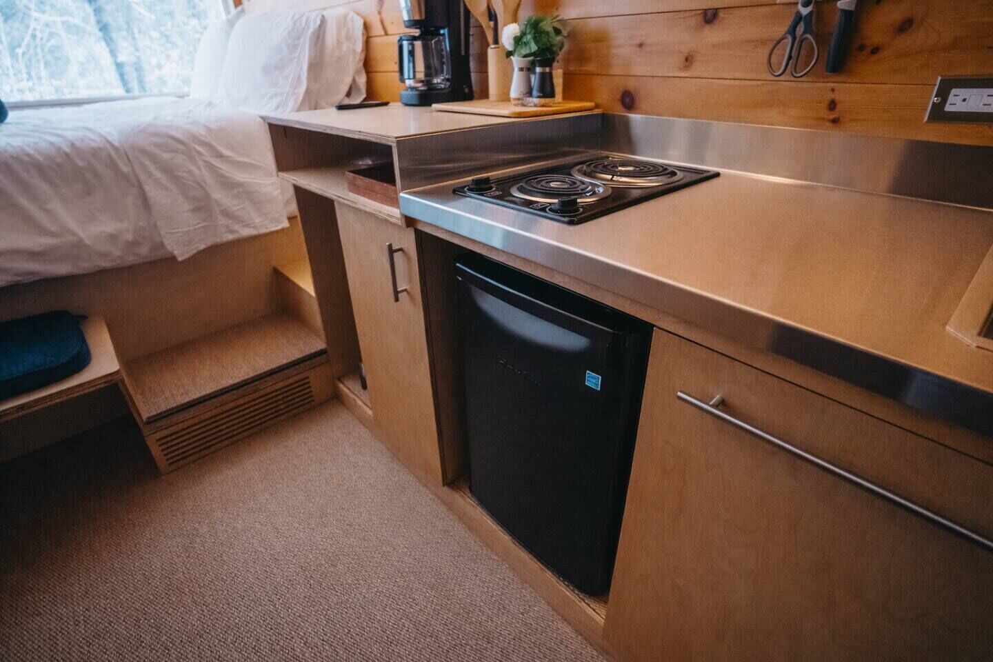 A compact kitchenette with a stove, sink, and a small refrigerator.