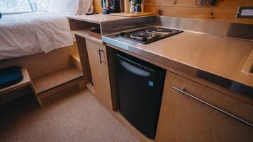 A compact kitchenette with a stove, sink, and a small refrigerator.